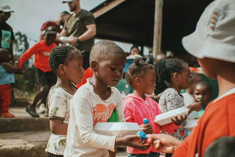Children receiving warm meals served by volunteers at a community distribution